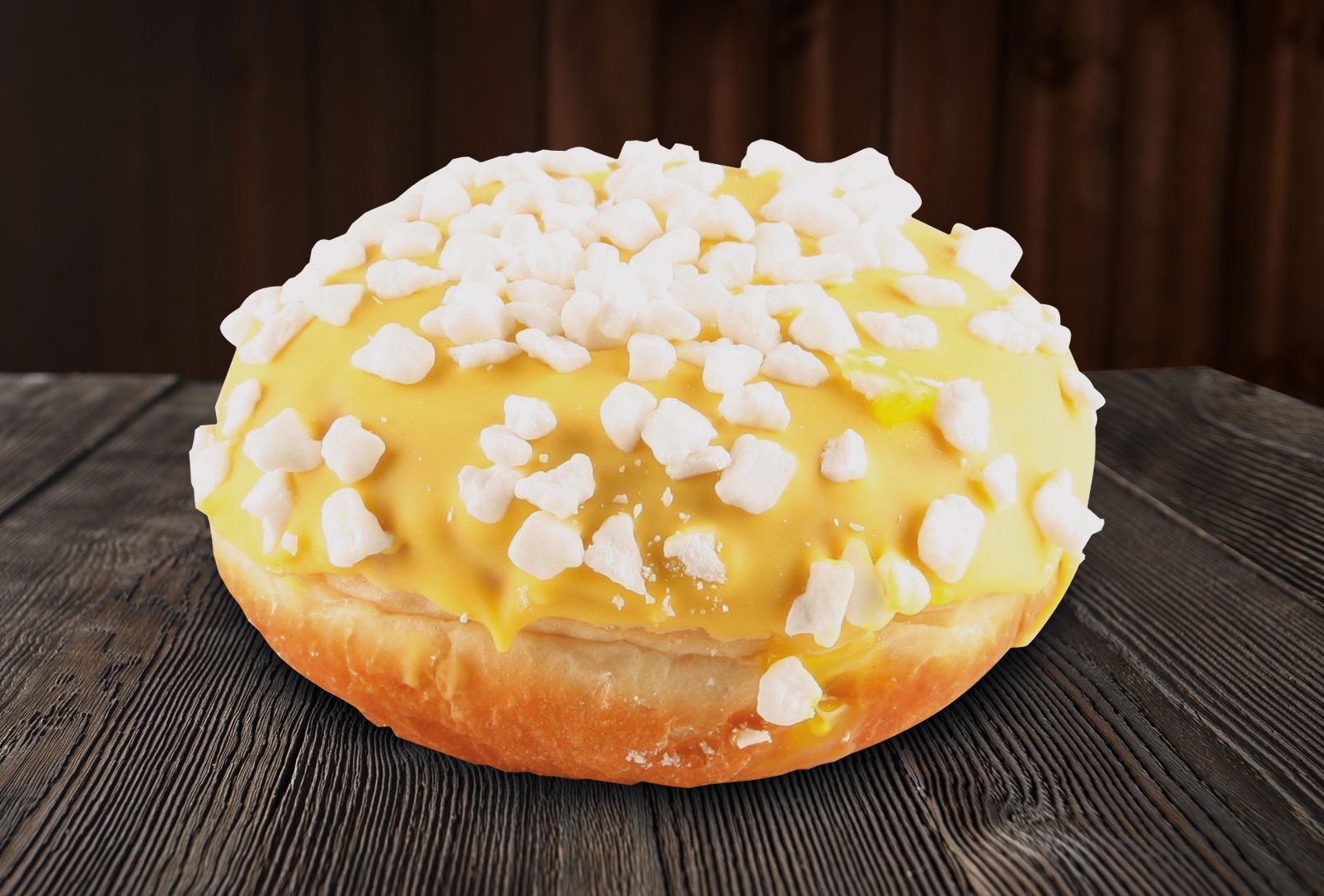 A donut with yellow frosting and white sprinkles on a wooden table.