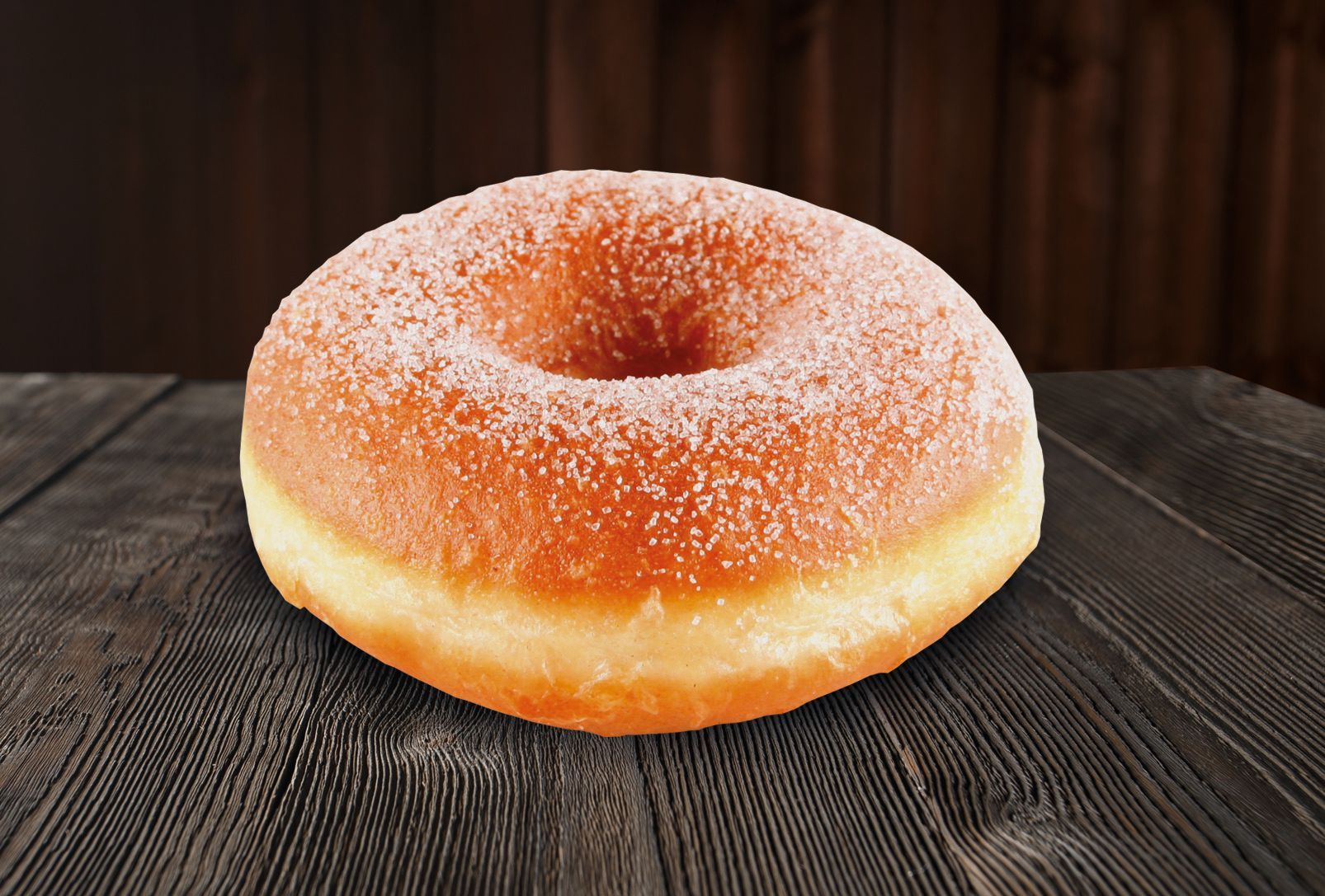 A donut with powdered sugar on it is sitting on a wooden table.