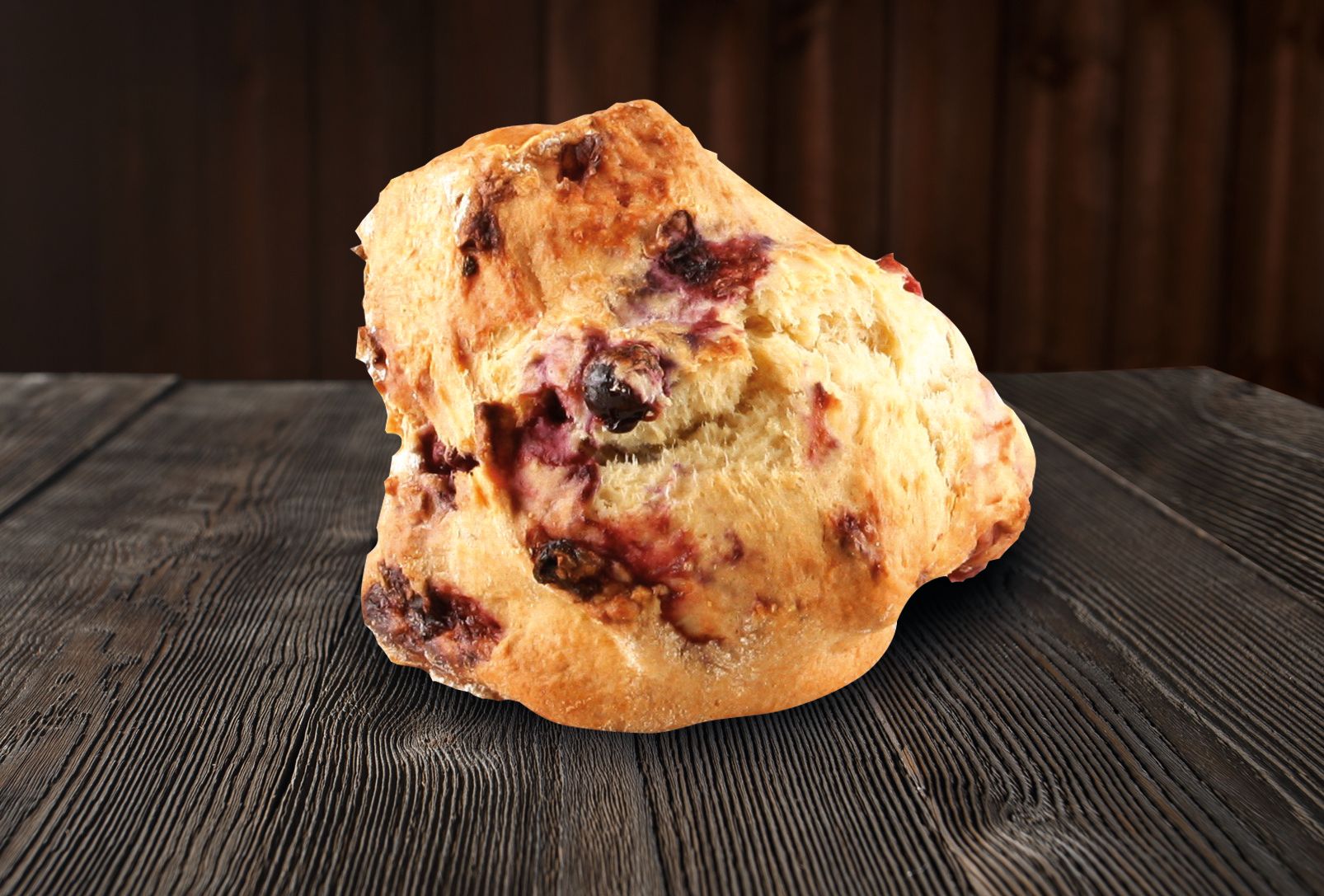 A blueberry muffin is sitting on a wooden table.