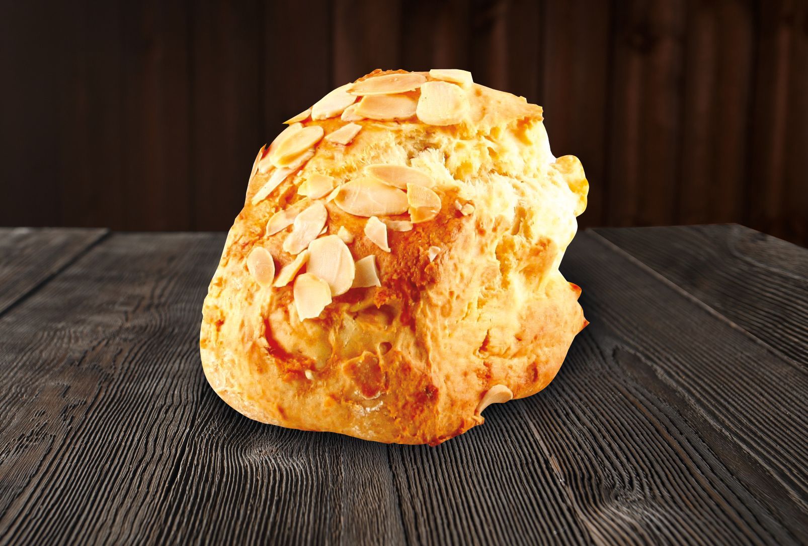 A piece of bread with almonds on it is on a wooden table.