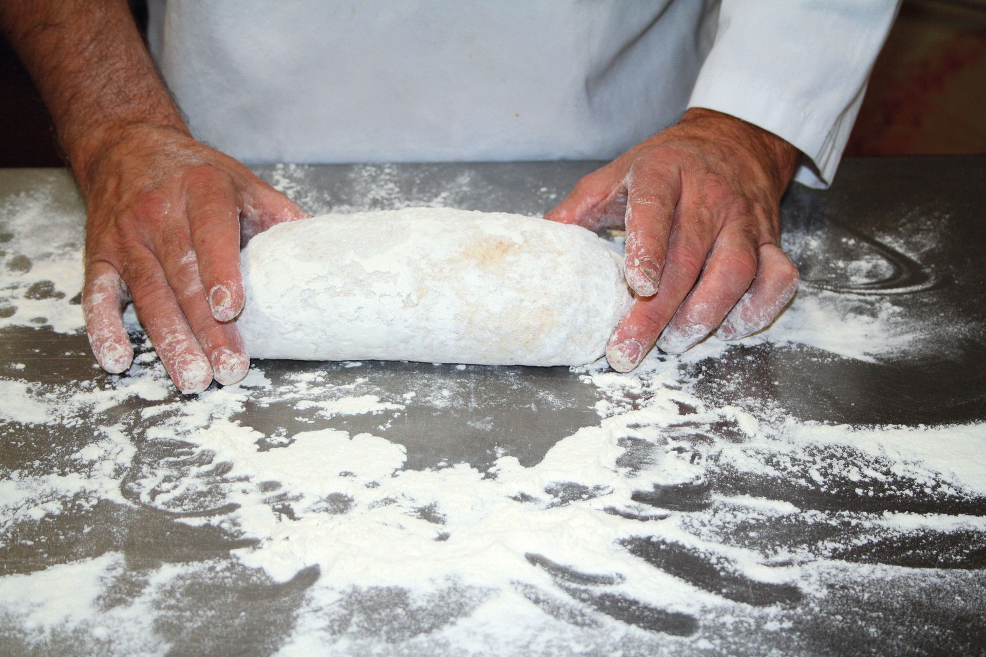 A person is rolling a piece of dough on a table