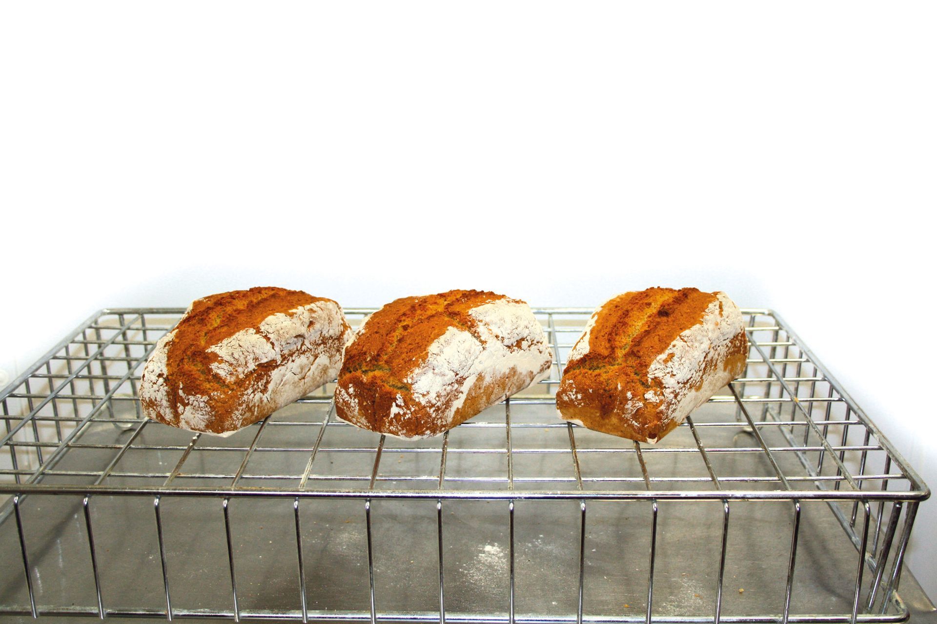 Three loaves of bread are sitting on a wire rack