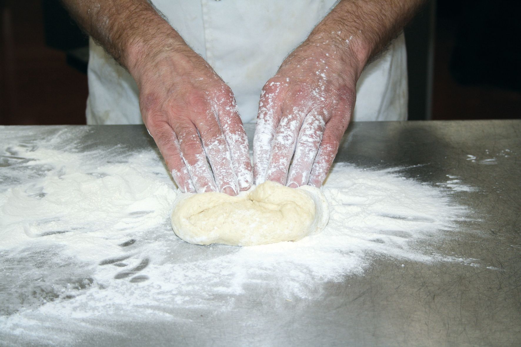 A person is kneading dough on a table covered in flour