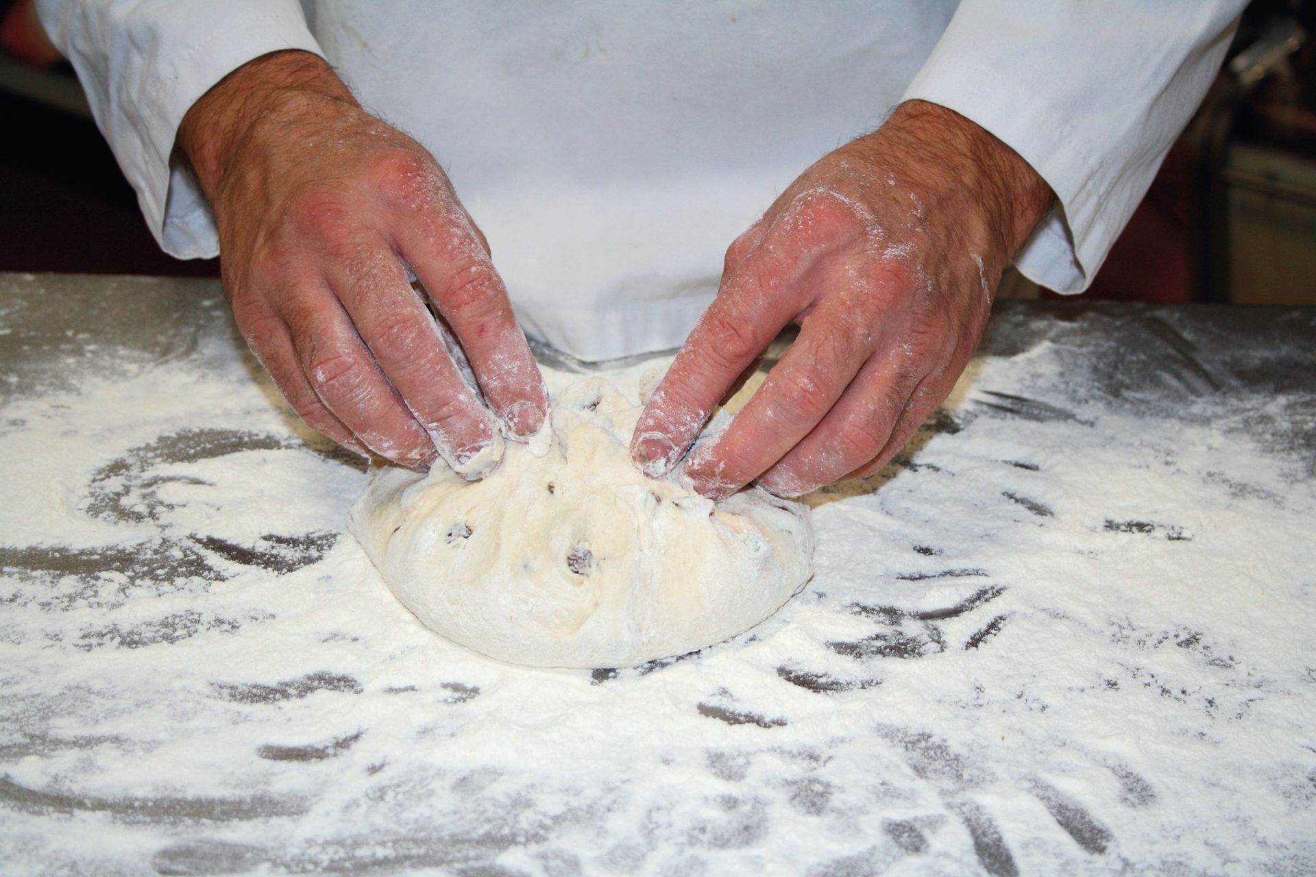 A person is kneading a piece of dough on a table