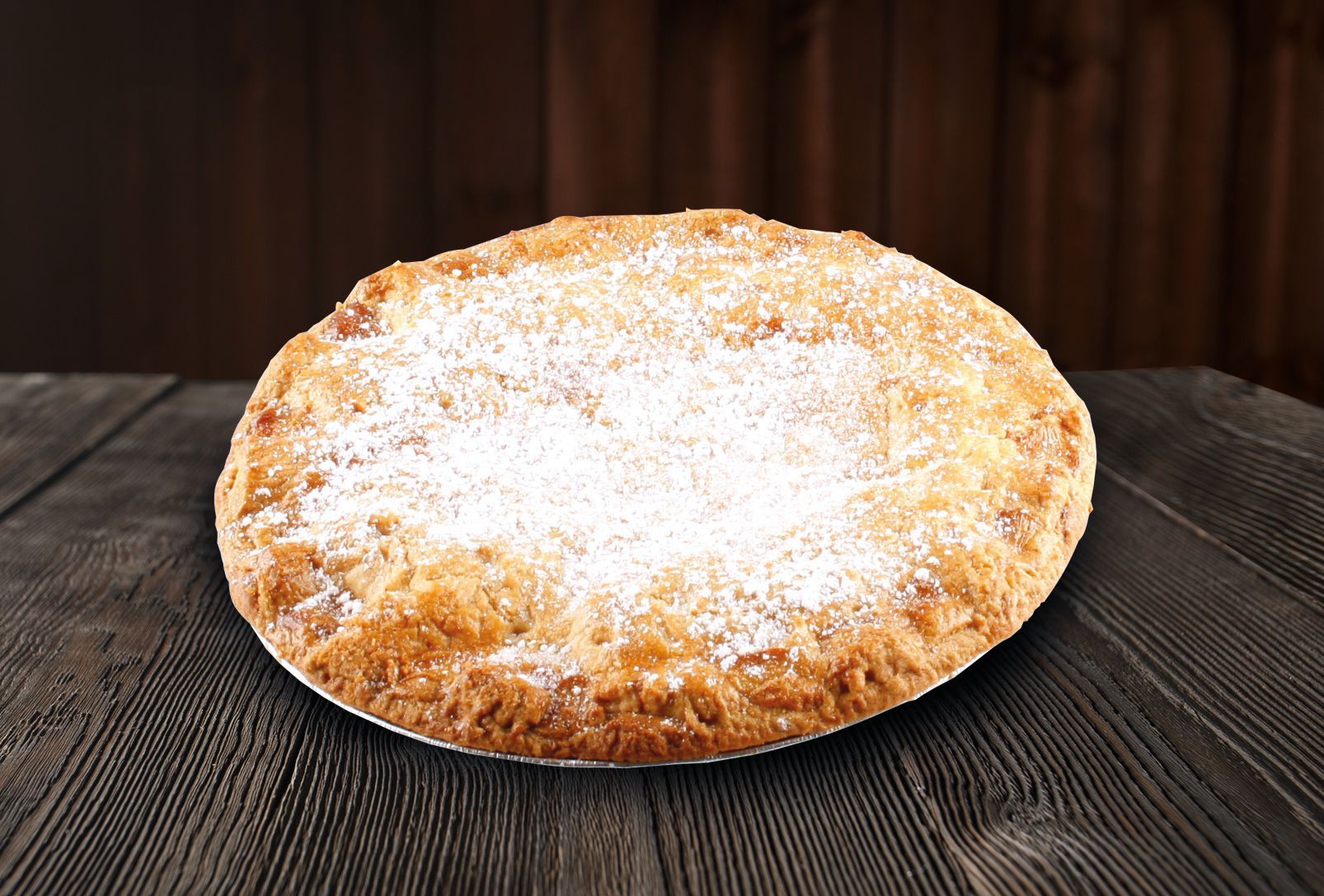 A pie with powdered sugar on top is sitting on a wooden table.