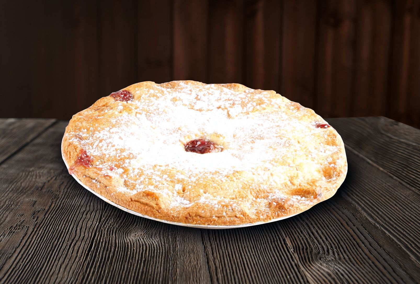 A pie with powdered sugar on top is sitting on a wooden table.