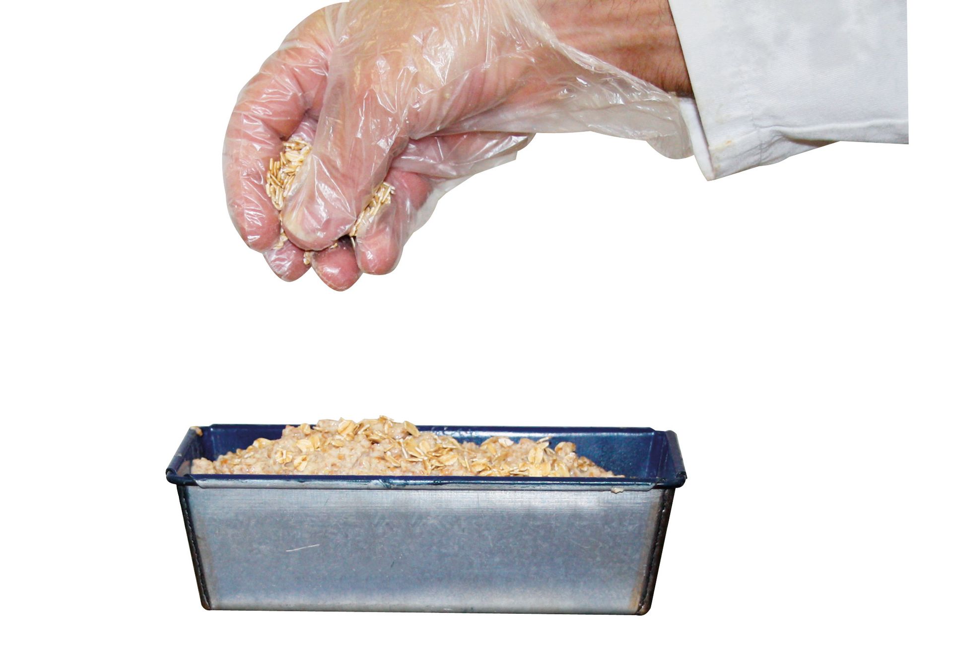 A person wearing plastic gloves is pouring food into a pan.