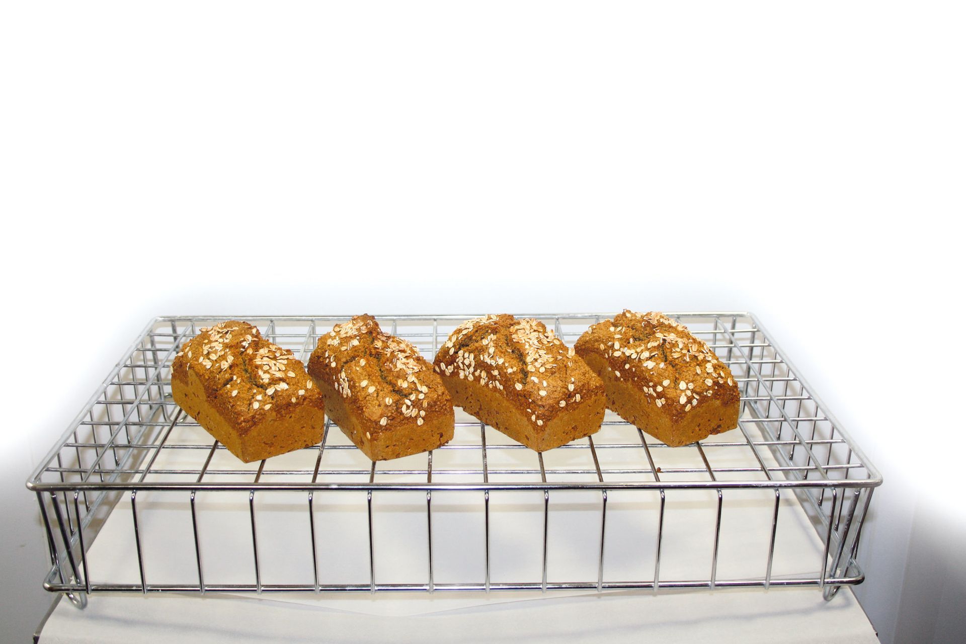 Four loaves of bread are sitting on a wire rack.