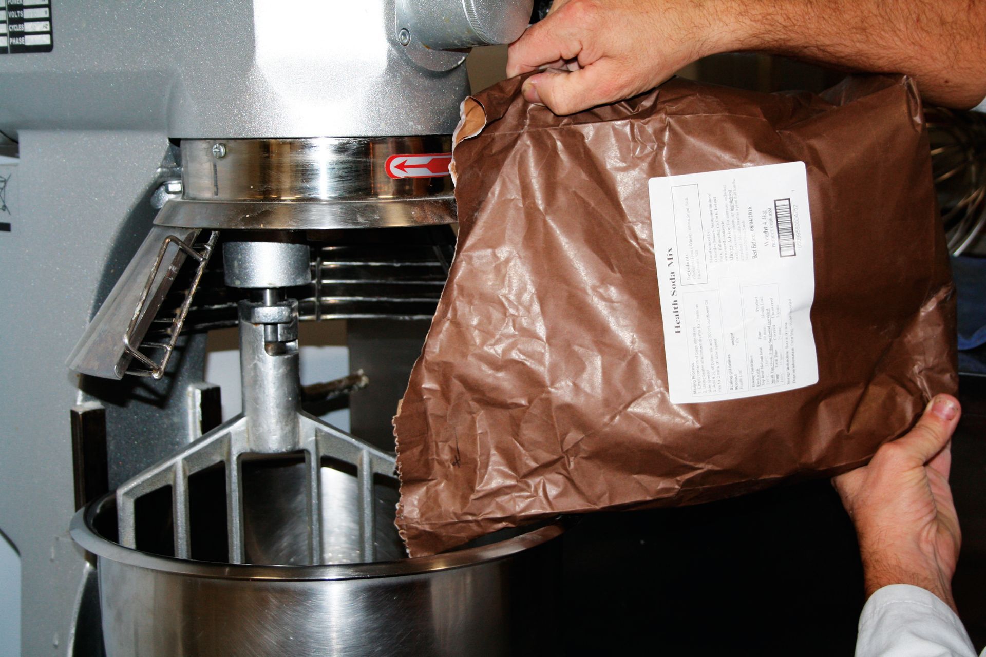 A person is pouring a brown bag into a mixer