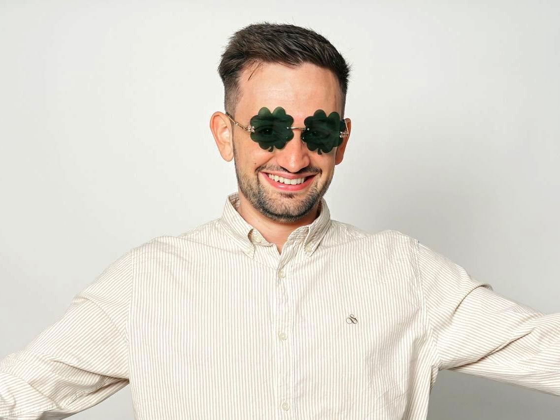A man wearing sunglasses with four leaf clovers on his eyes.