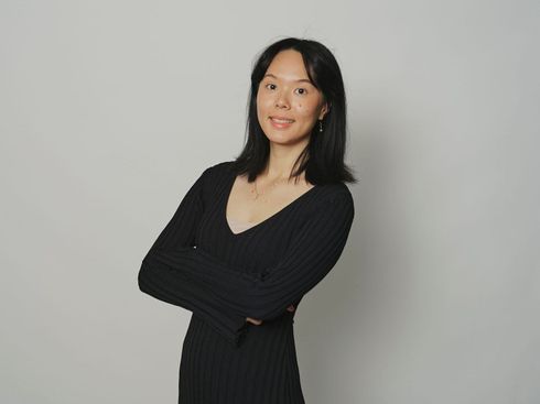 A woman in a black sweater is making a peace sign with her hands.