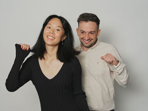 A man and a woman are posing for a picture together . the woman is holding the man 's hair.
