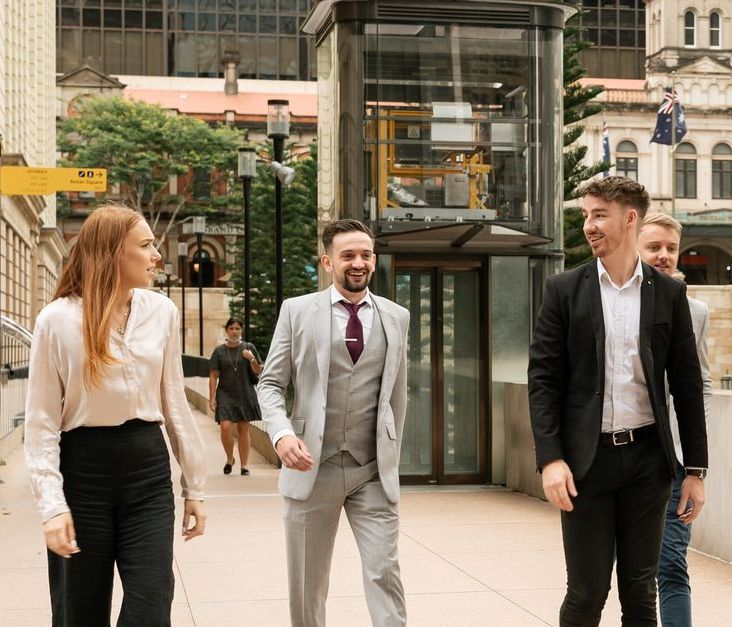 A group of people are walking down a sidewalk in a city.