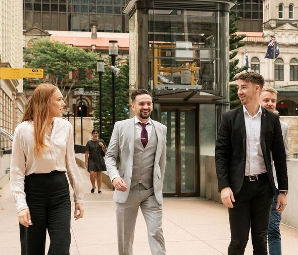 A group of people are walking down a sidewalk in a city.