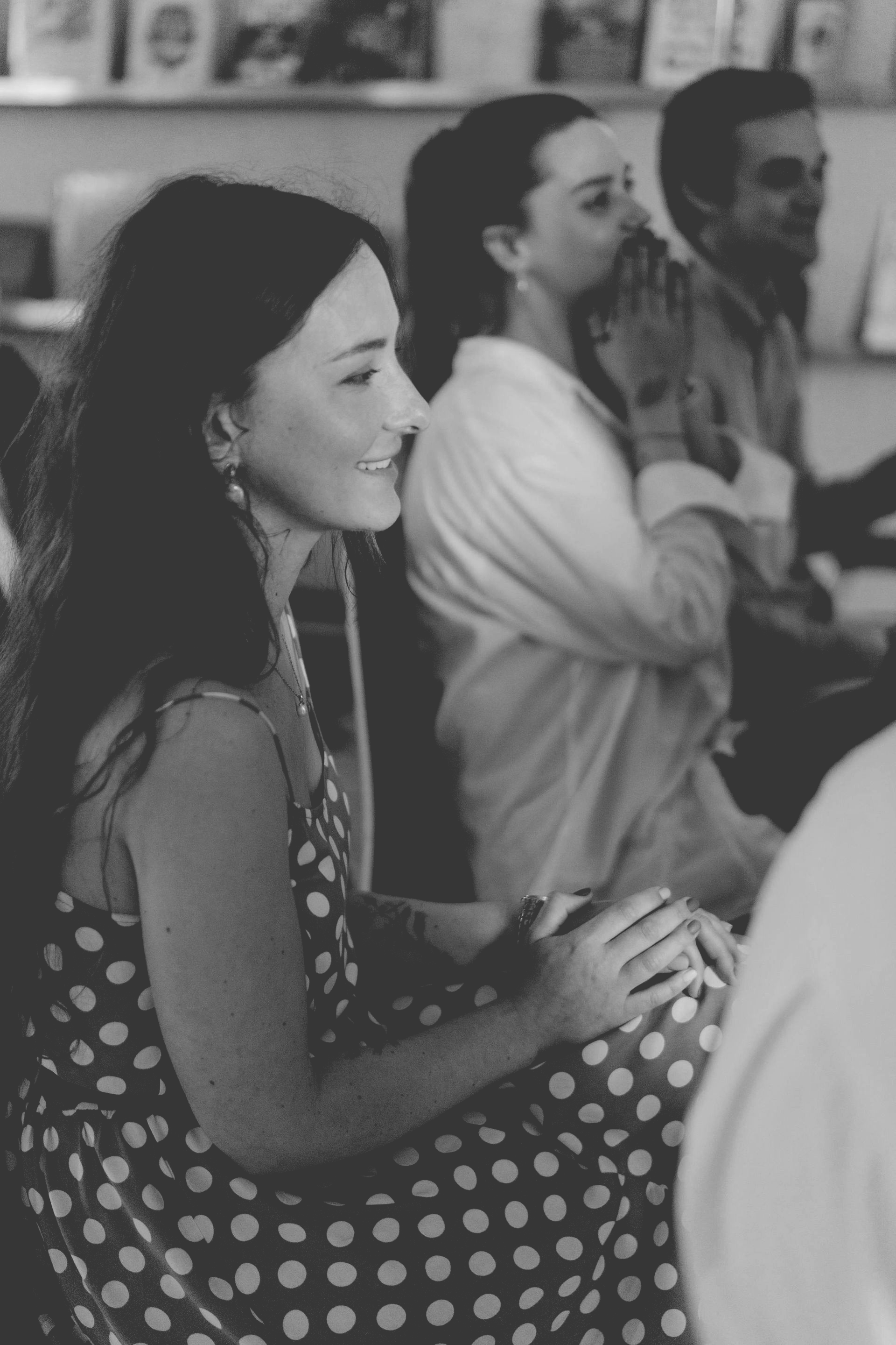Woman in polka dot dress smiles at an event with others.