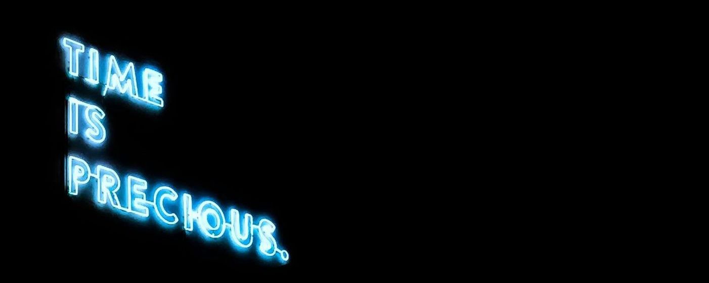 A neon sign that says `` time is precious '' on a black background.