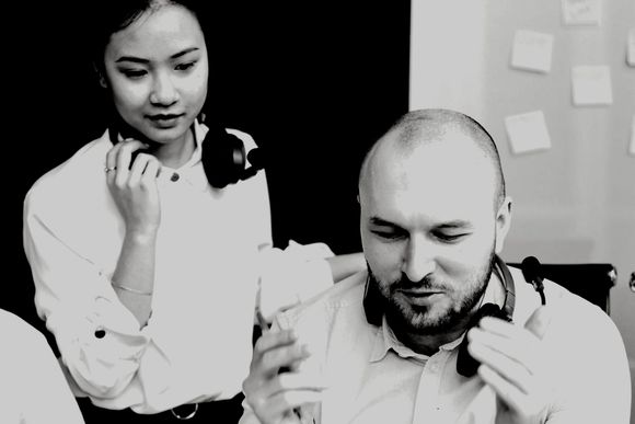 A woman is standing next to a man wearing headphones.