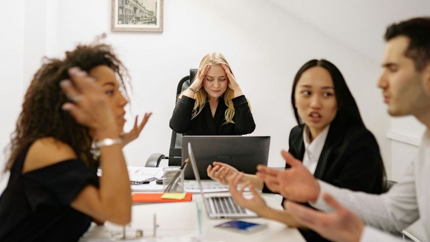A group of people are sitting around a table with laptops.