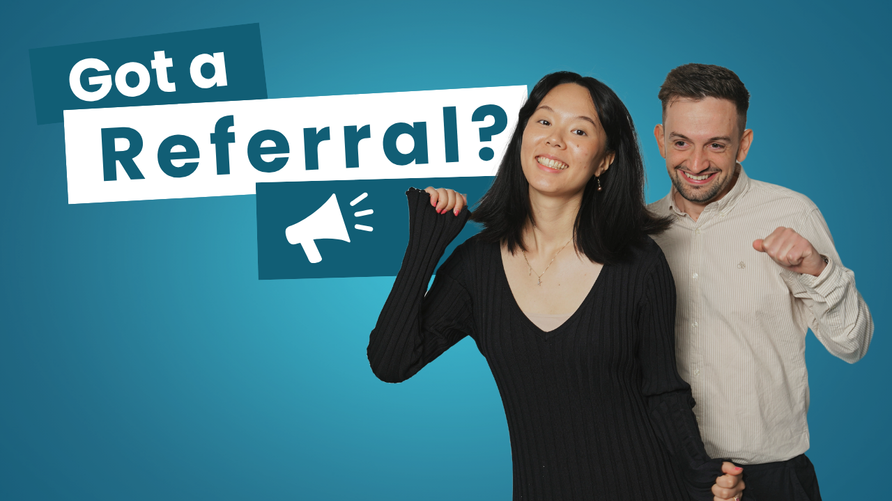 A man is standing next to a woman sitting in front of a computer.