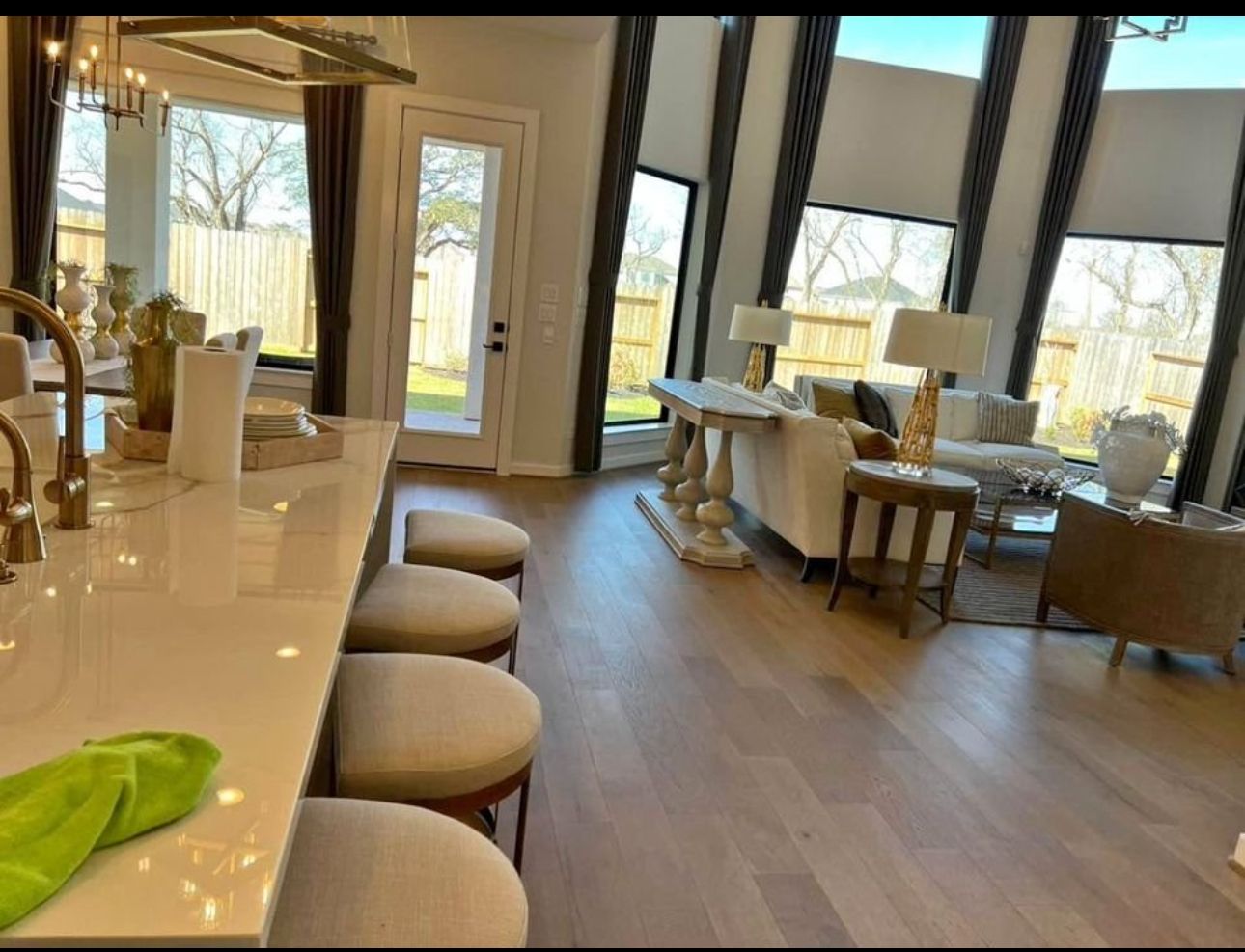 Modern living room with angled windows, light wood floors, and neutral-toned furniture.
