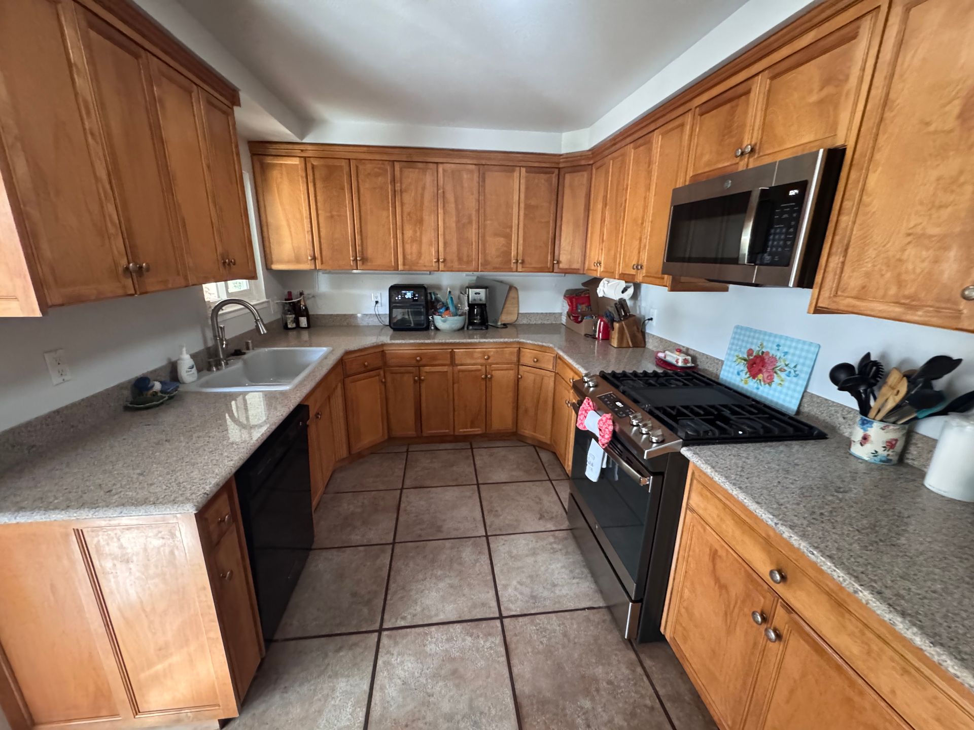 U-shaped kitchen with light brown cabinets, stainless steel appliances, and beige countertops.