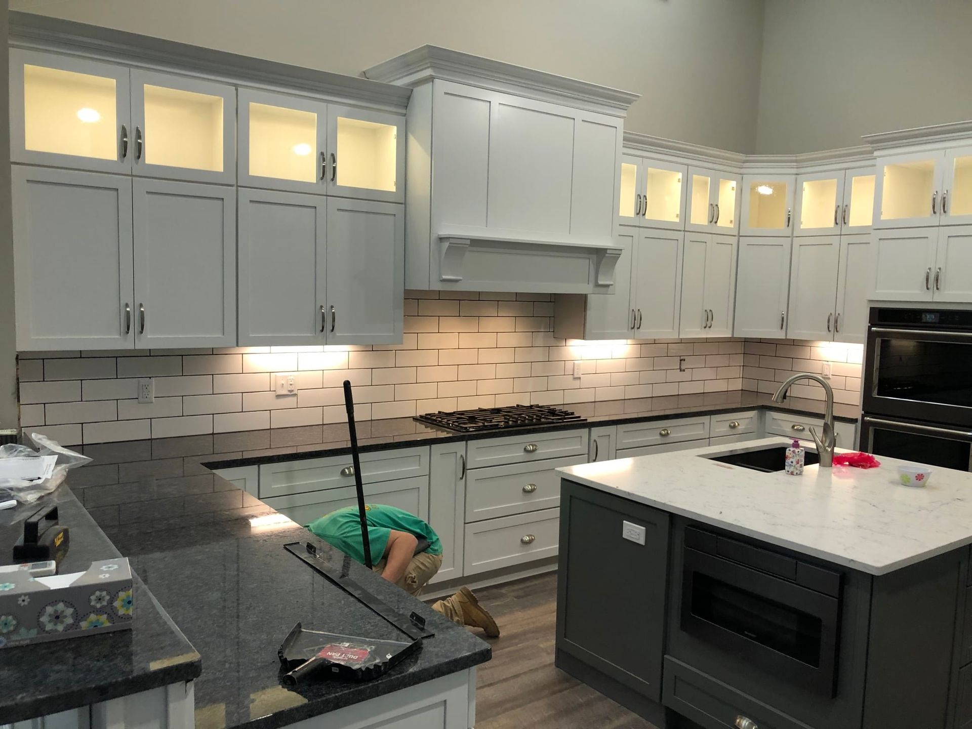 A kitchen with white cabinets , black counter tops , and a large island.
