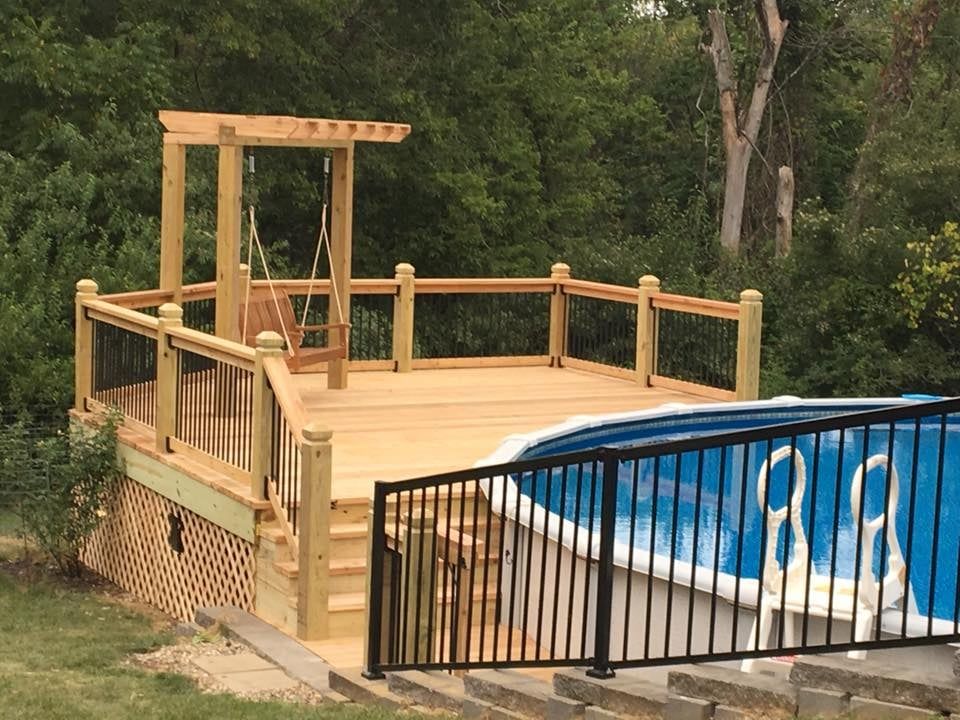 A wooden deck overlooking a swimming pool with stairs leading to it.