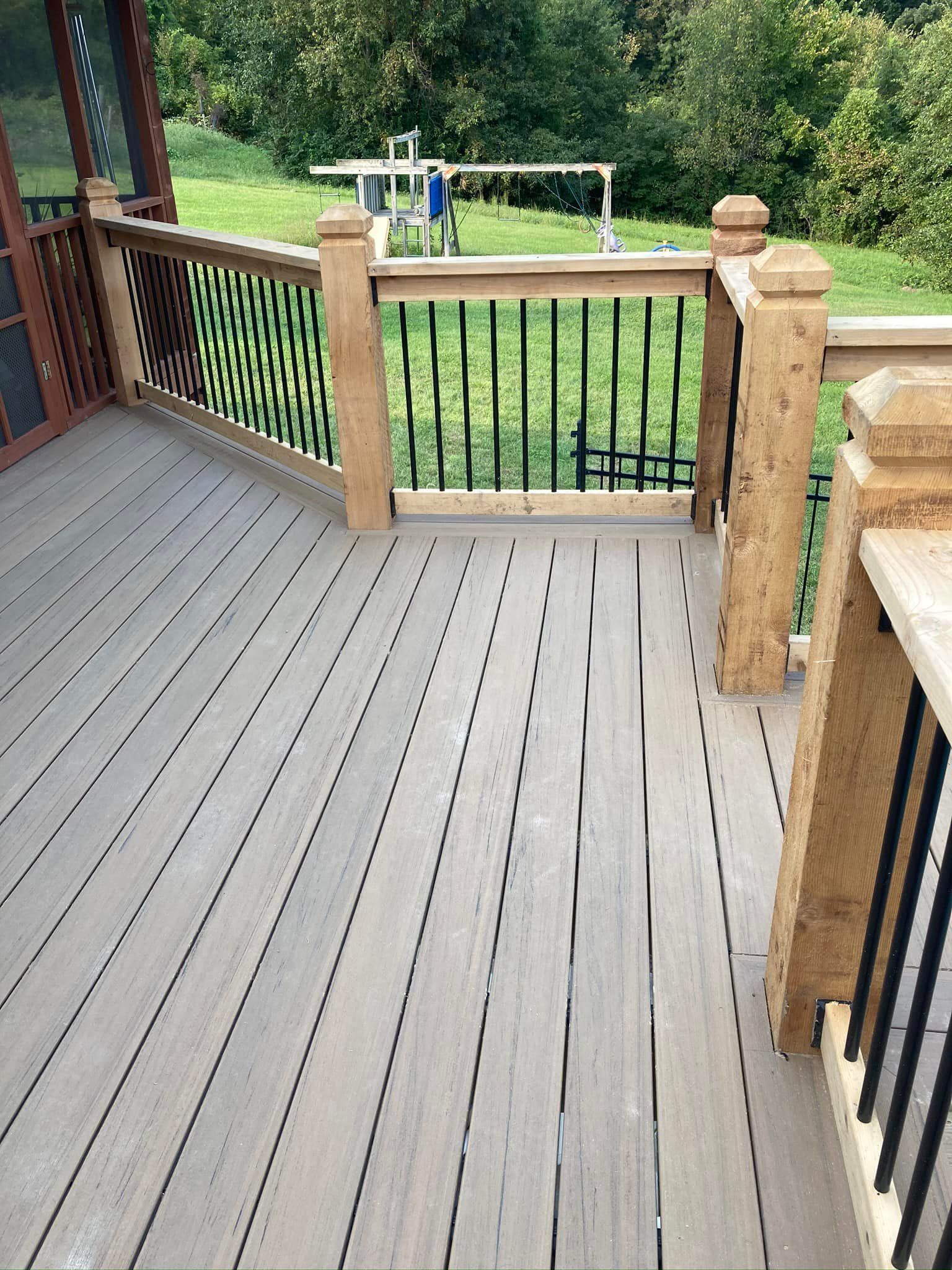 A wooden deck with a metal railing and a playground in the background.