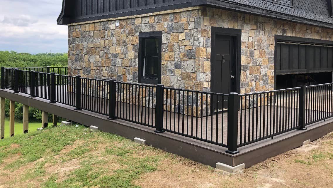 A stone building with a black fence around it and a deck.