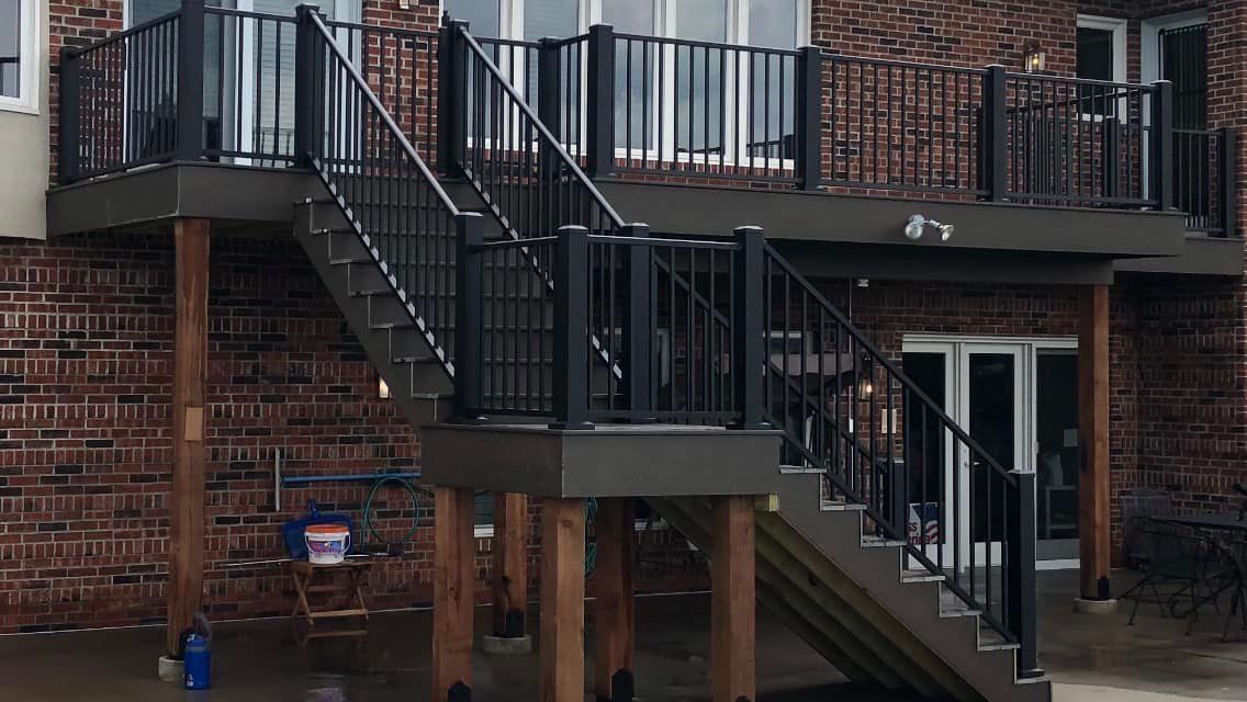 A deck with stairs leading up to a brick building.