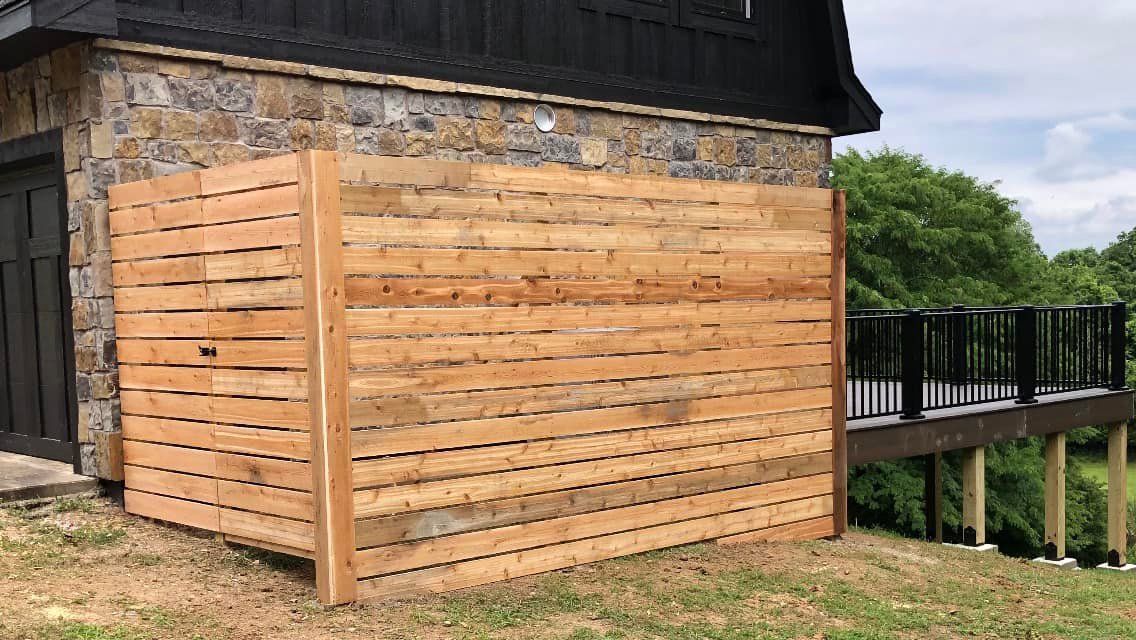 A wooden fence is sitting in front of a stone building.