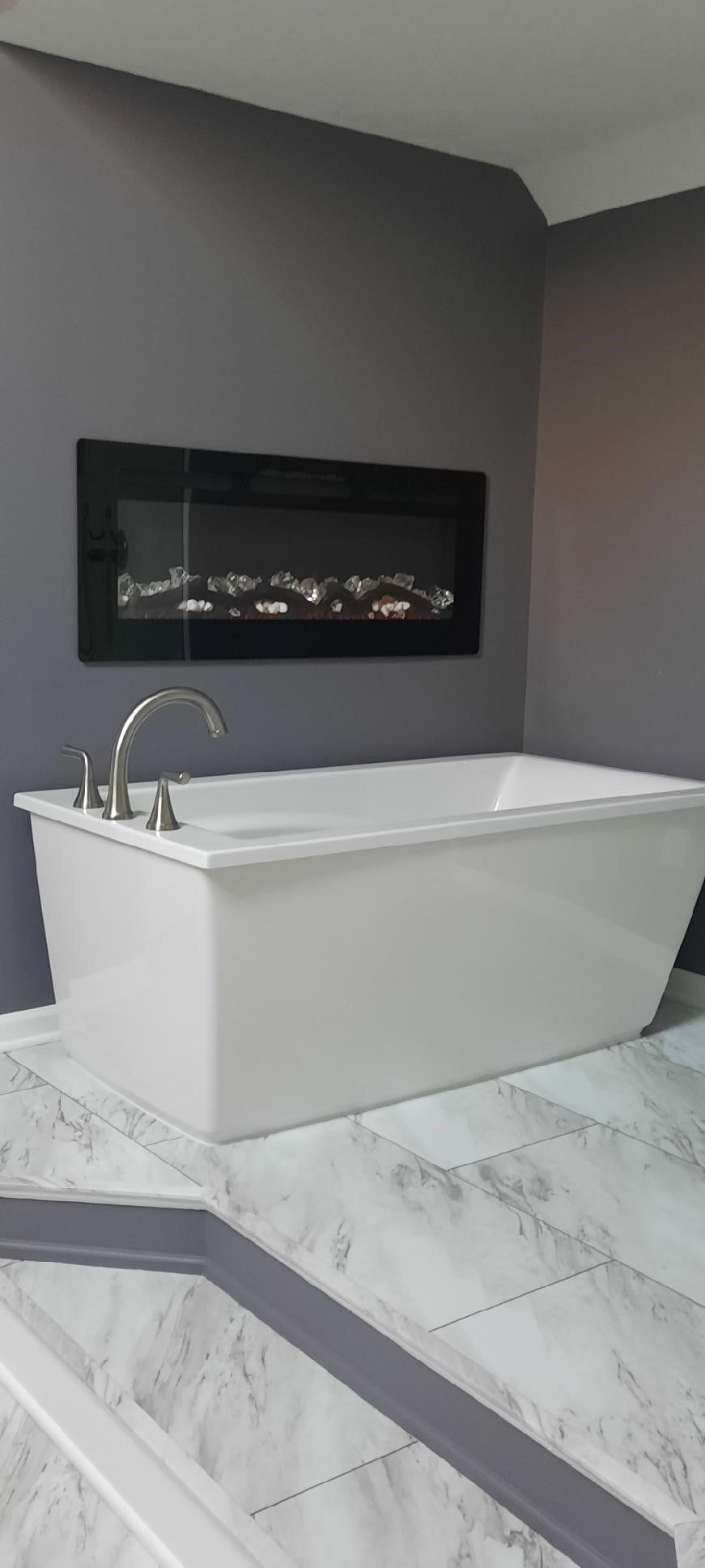 A white bathtub is sitting on top of a marble counter in a bathroom.