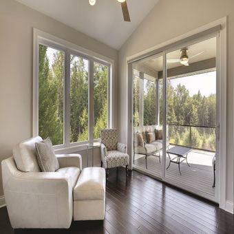 A living room with a couch , chair , ottoman and sliding glass doors.