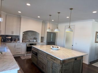 A living room with a couch , chair , ottoman and sliding glass doors.