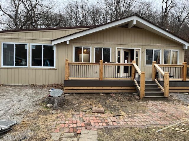 Tan house with deck and several large windows. Exterior view, gray sky.