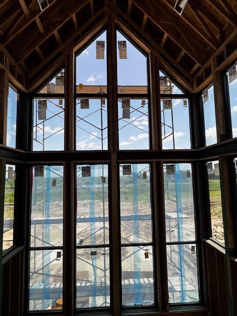 Interior view of a building under construction featuring tall, multi-pane windows with a sky view.