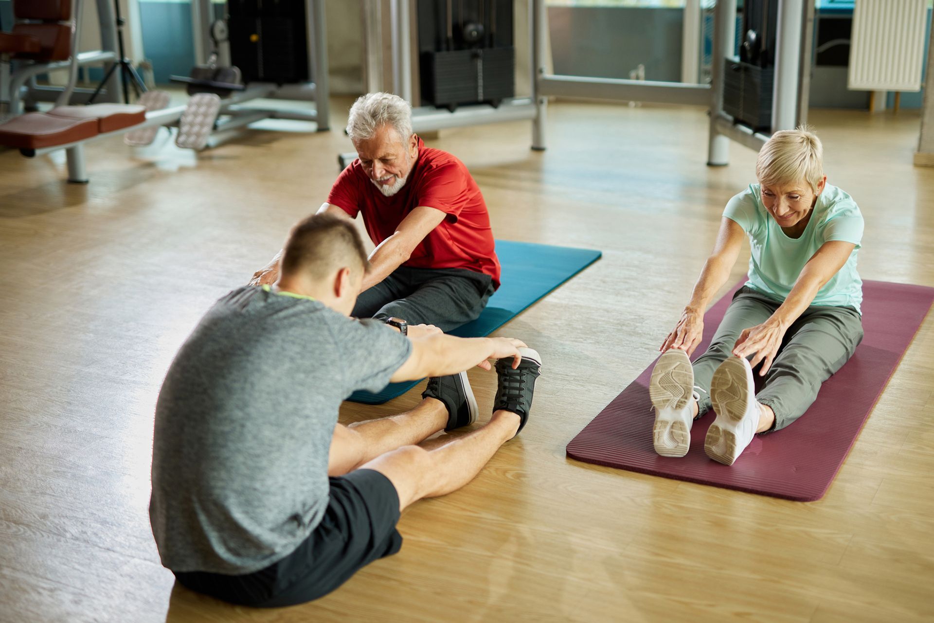 Un gruppo di persone si sta allungando sui tappetini da yoga in una palestra.