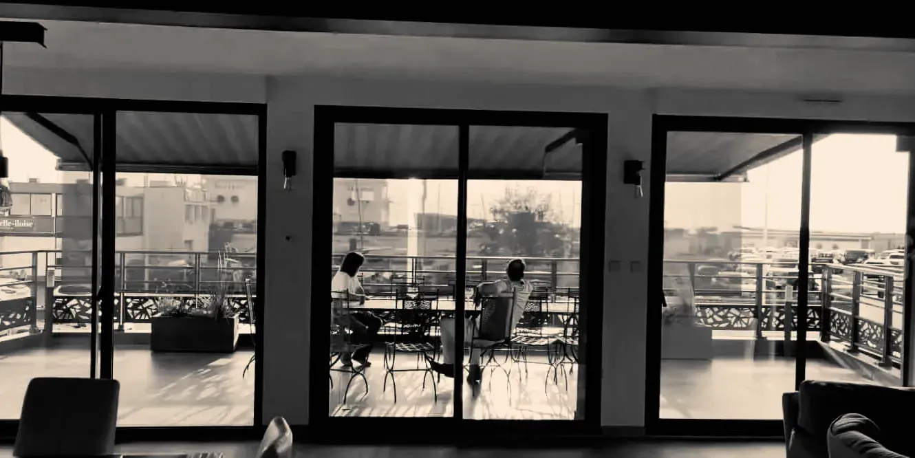 Une photo en noir et blanc d'un salon avec beaucoup de fenêtres.