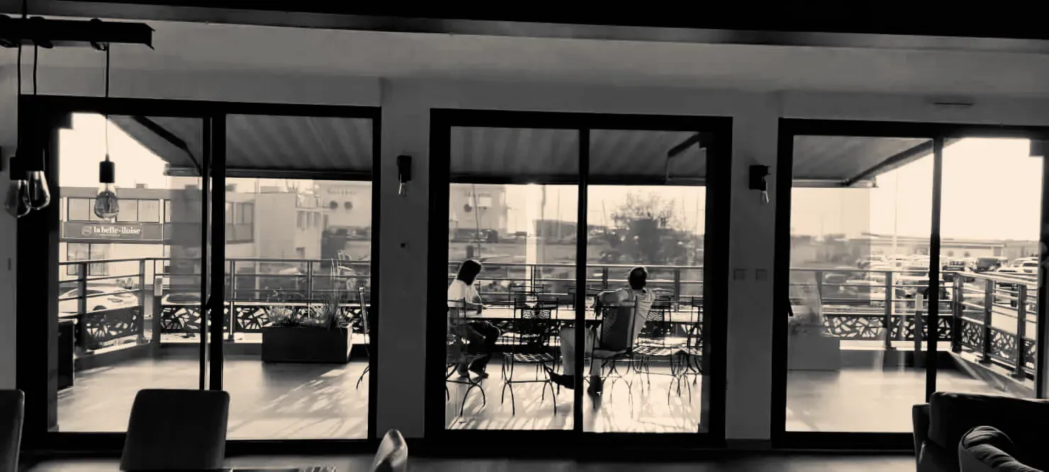 Une photo en noir et blanc d'un salon avec beaucoup de fenêtres et un balcon.