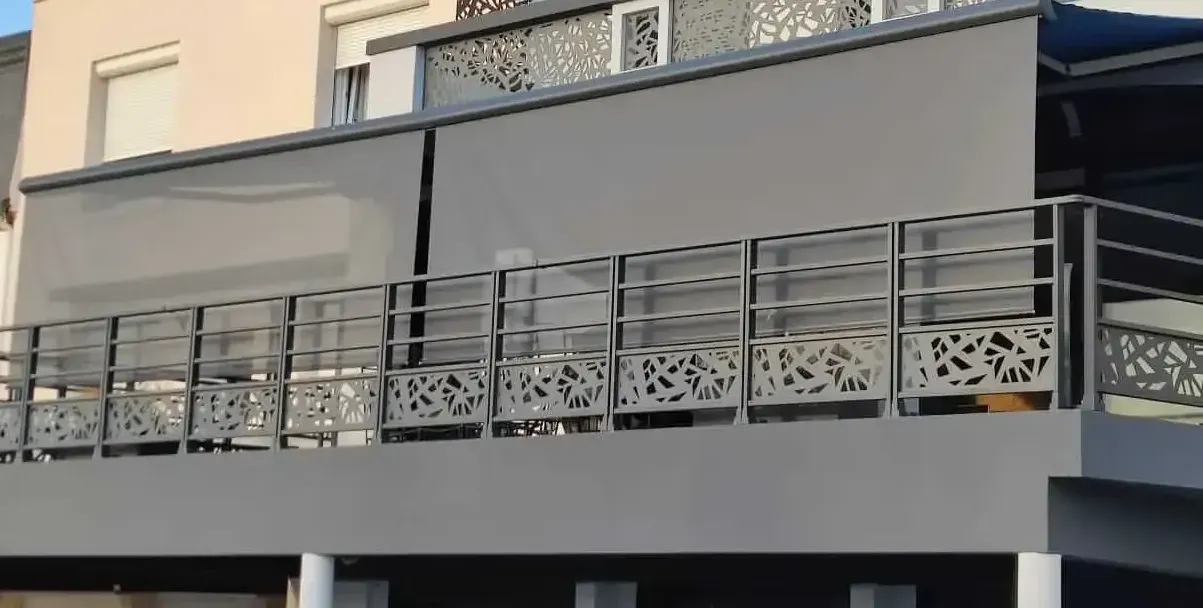 Un balcon avec une balustrade en métal et des stores dessus.
