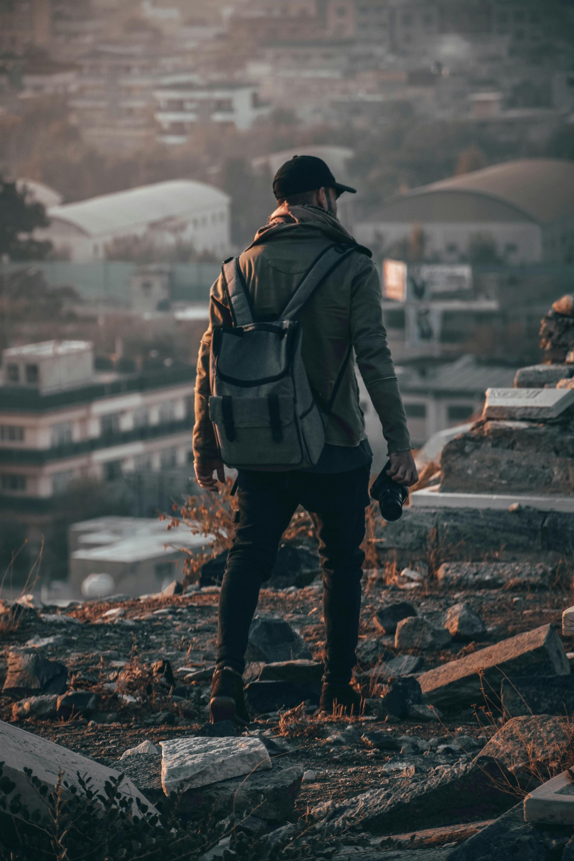 Un homme avec un sac à dos se tient au sommet d'une colline rocheuse.