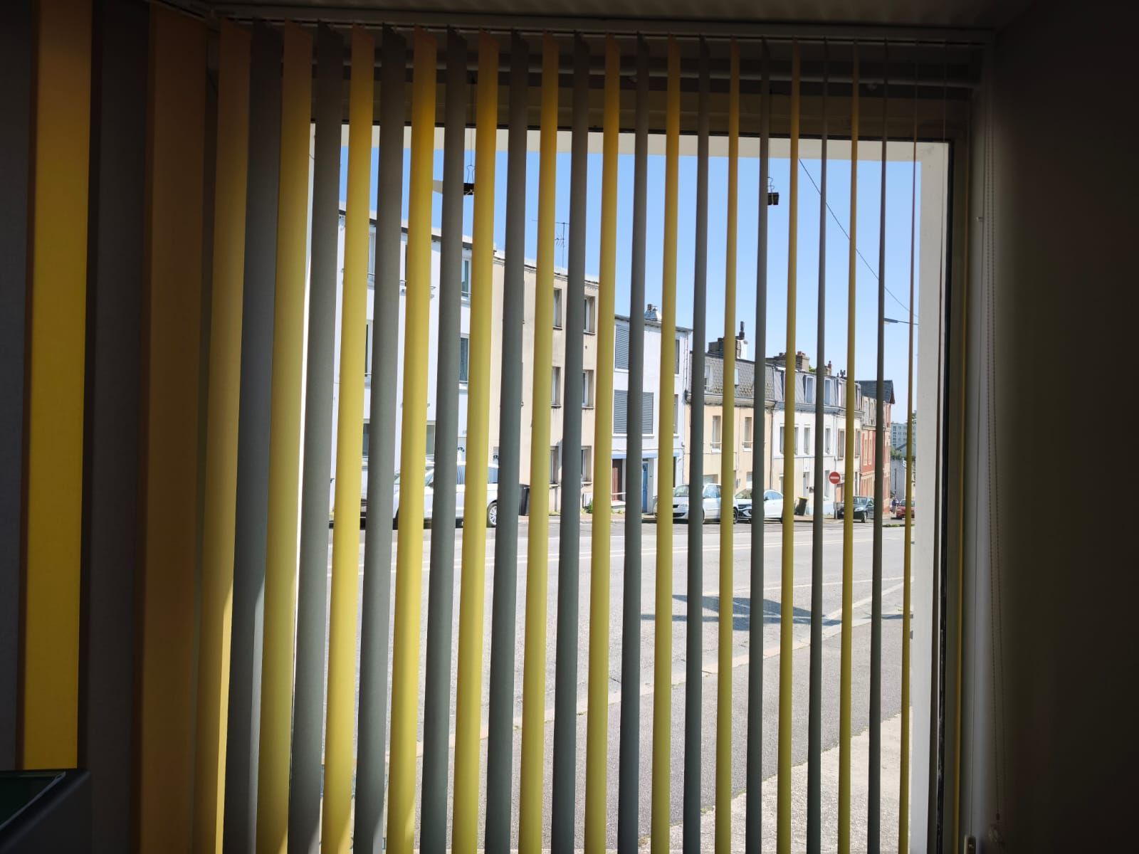 Une fenêtre avec des stores verticaux jaunes et gris dessus