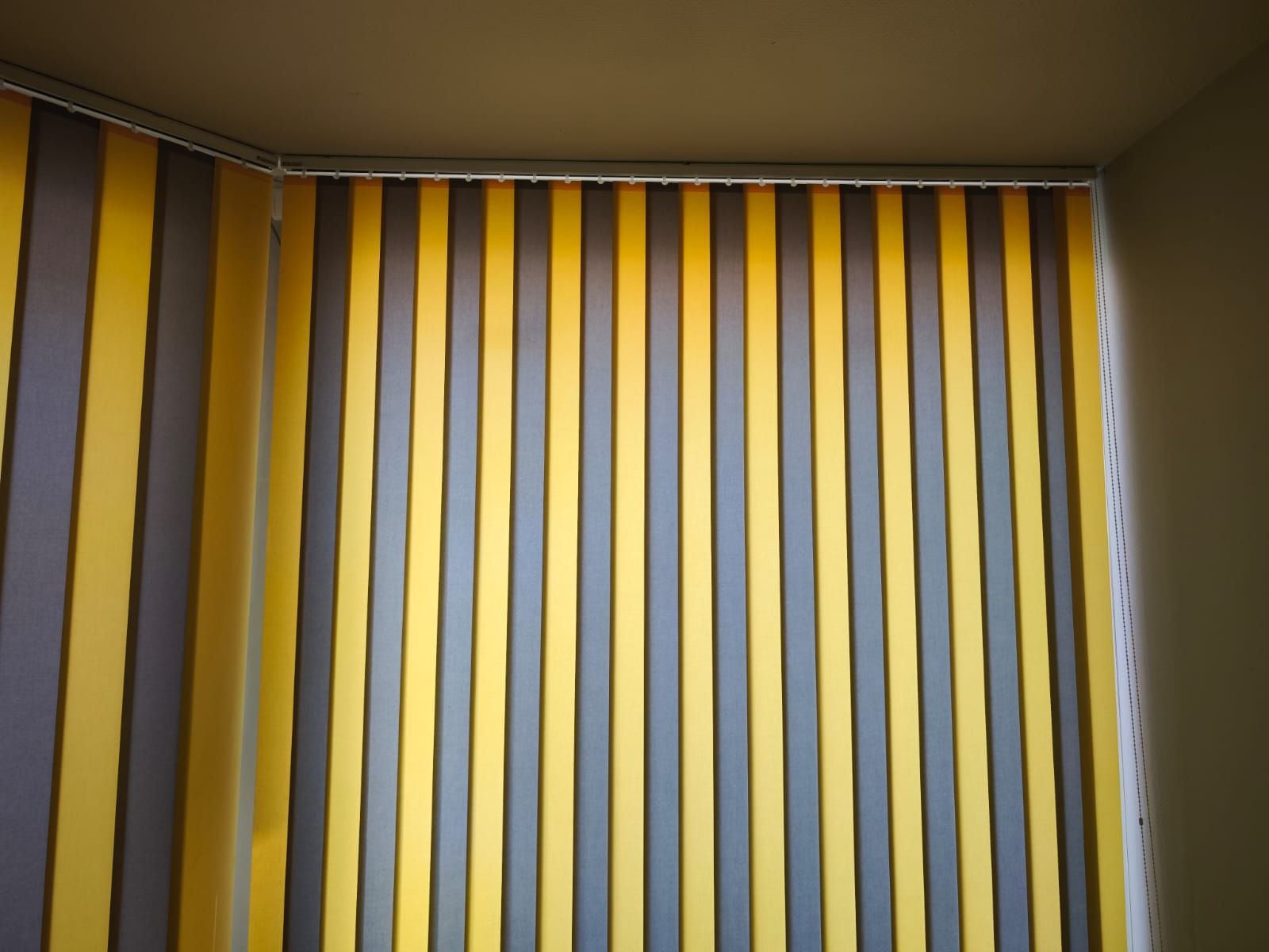 Une pièce avec des stores verticaux jaunes et gris