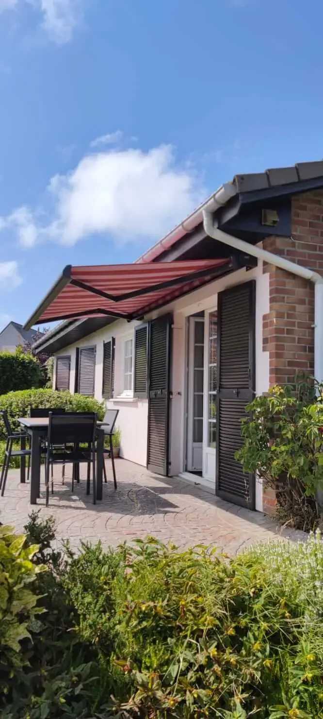 Une maison avec un patio avec une table et des chaises sous un auvent.