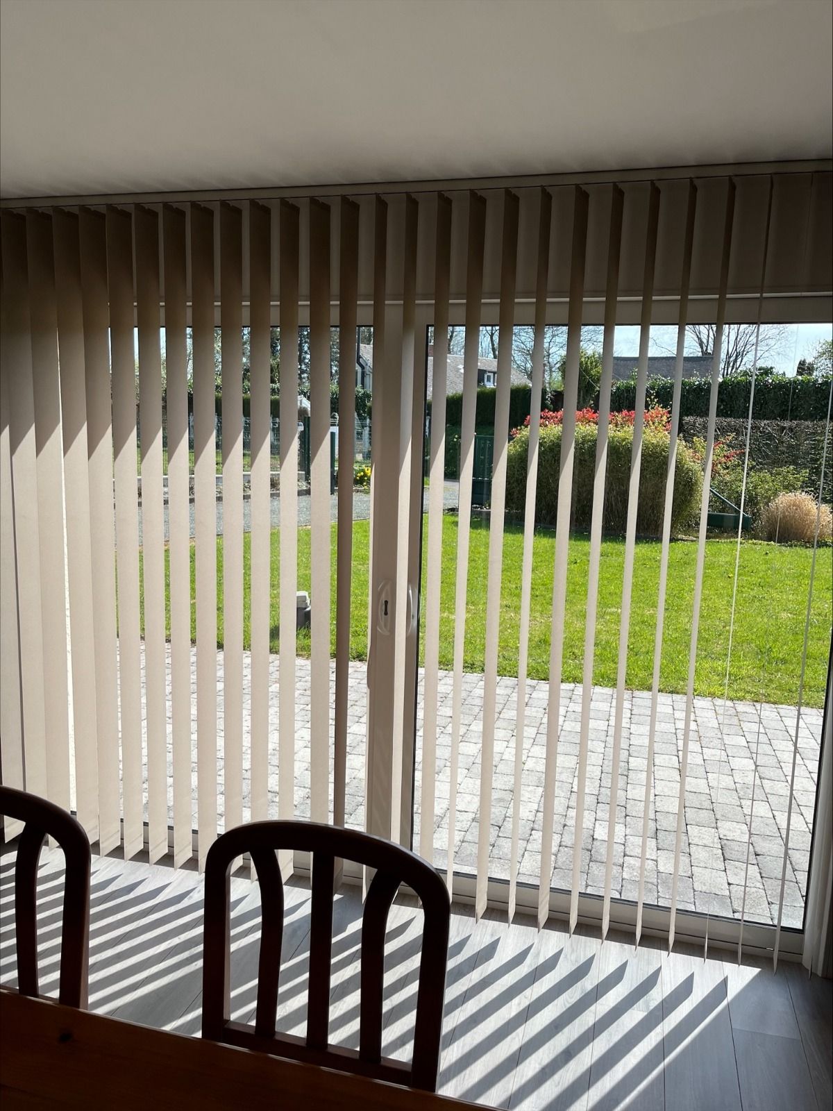 Une salle à manger avec une table et des chaises et une porte coulissante en verre avec stores verticaux.