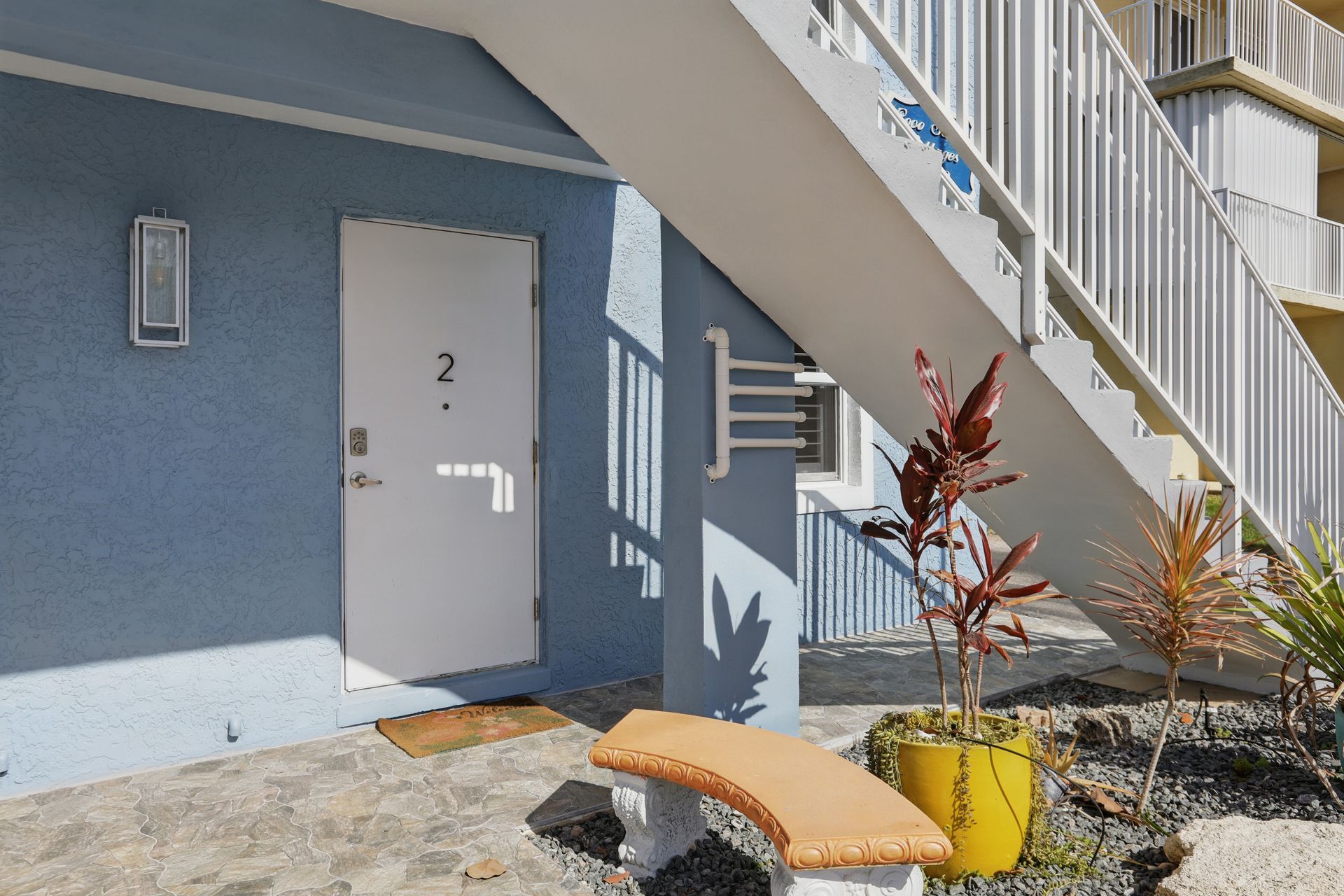 A blue building with stairs and a bench in front of it