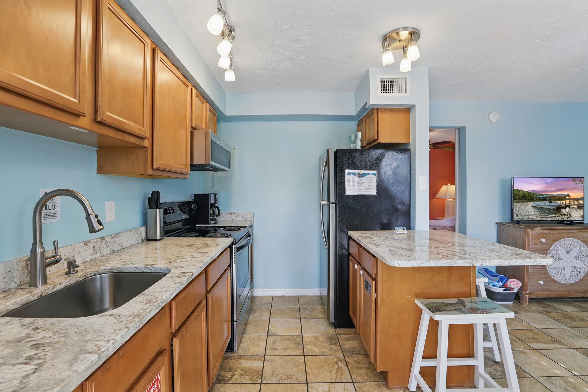 A kitchen with a sink , refrigerator , stove , and television.