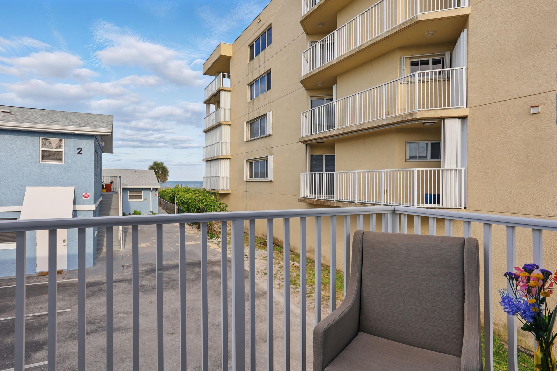A balcony with a chair and flowers in front of a building