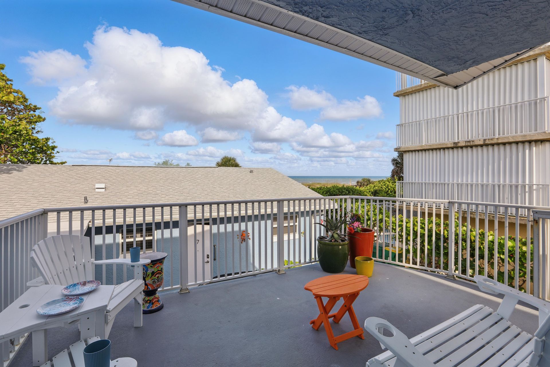 A balcony with chairs and a table with a view of the ocean