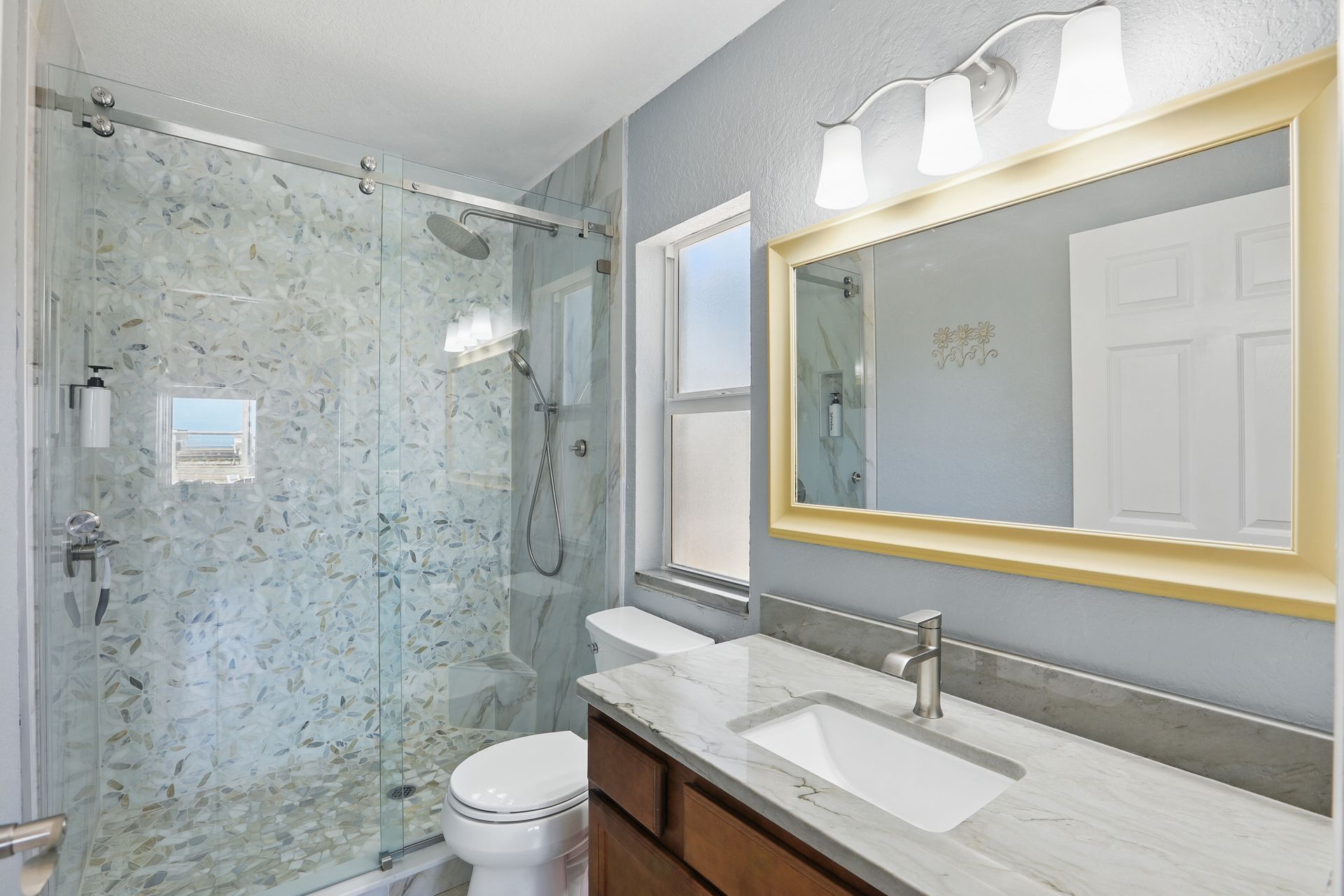 A bathroom with a toilet , sink , shower and mirror.